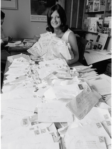 Woman shows thousands of signed forms, covering the desk and filling the room