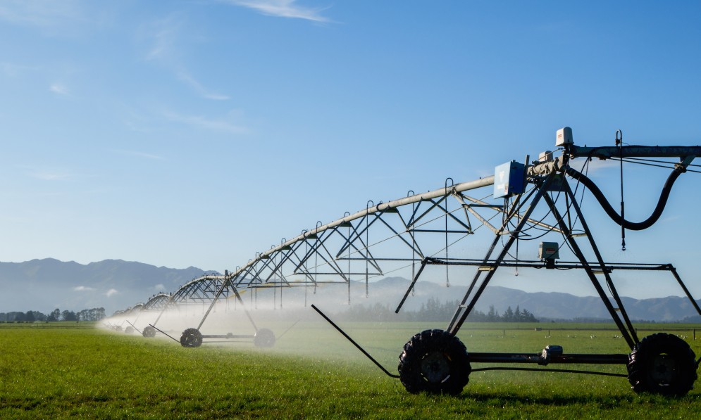 A pivot irrigator spraying water over farmland