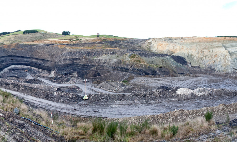 open cast coal mine with black dirt, dug-out rock, and gravel roads