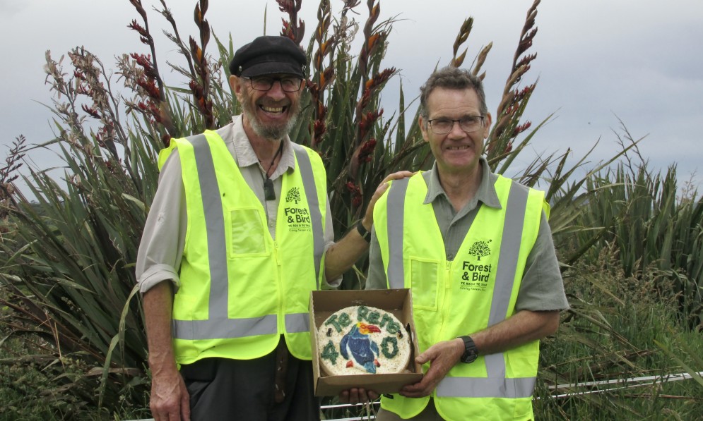 Te Rere stalwarts Fergus Sutherland (left) and Brian Rance (right) standing together in the reserve with a 40th birthday cake between them