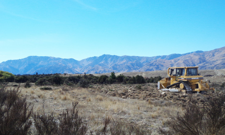 Otago Hawea river terraces being cleared by a bulldozer of mixed kanuka grey shrubland and grassland cushion field ecosystem
