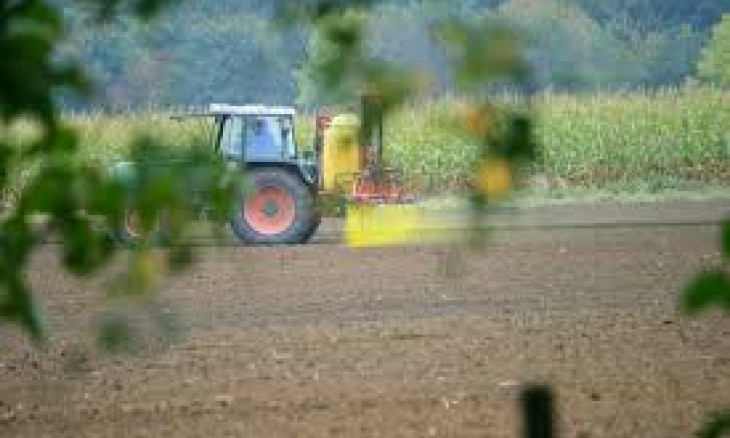 Tractor spraying pesticides onto a farm